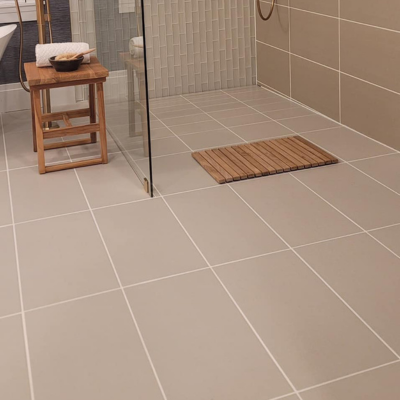 Michigan home with minimalist bathroom with taupe tiles, glass shower, and wooden stool.